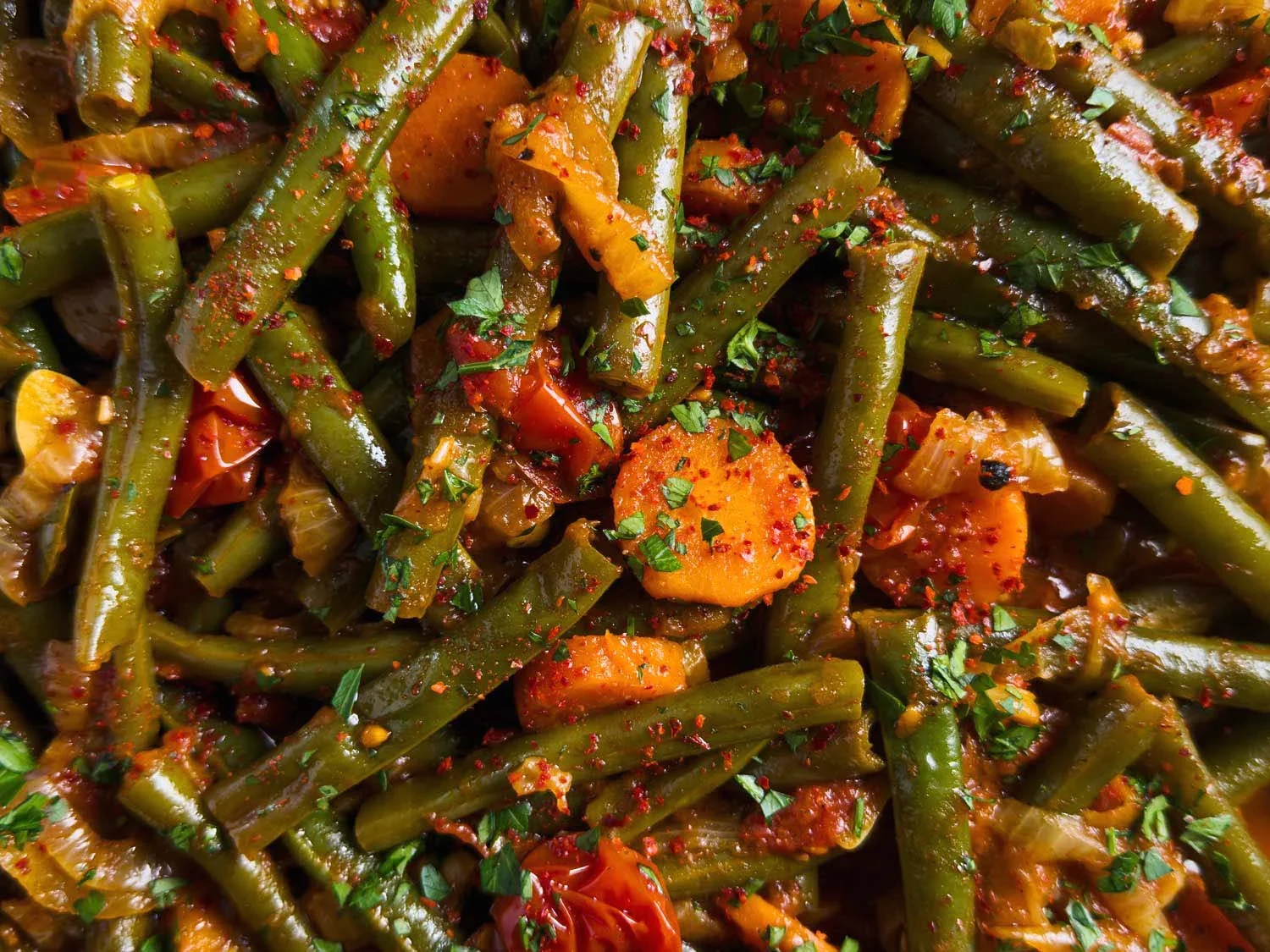 Sautéed green beans with carrot slices, onions, and chopped parsley, seasoned with red pepper flakes